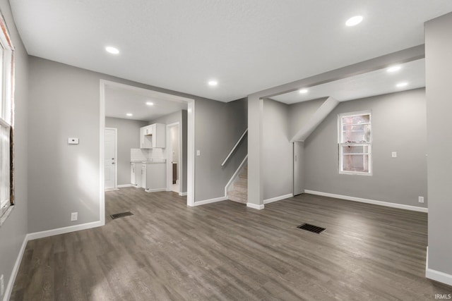 below grade area with visible vents, baseboards, dark wood-style floors, and stairway