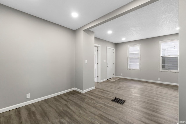 spare room with recessed lighting, visible vents, baseboards, and dark wood-type flooring