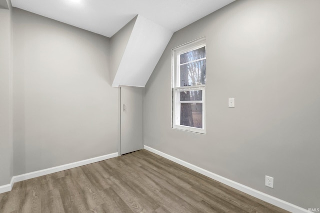 additional living space featuring lofted ceiling, baseboards, and wood finished floors