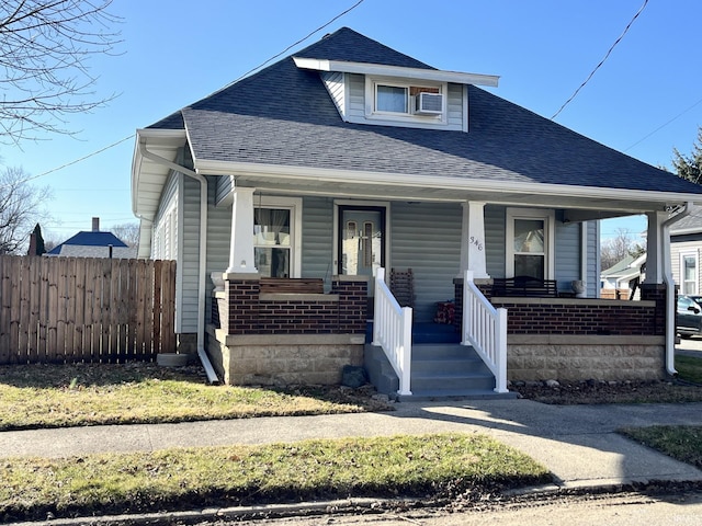 bungalow with a porch, fence, and a shingled roof