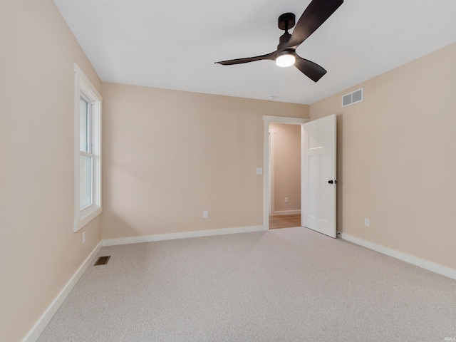 spare room with ceiling fan, baseboards, visible vents, and light carpet