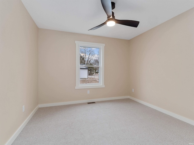 carpeted spare room featuring a ceiling fan, visible vents, and baseboards