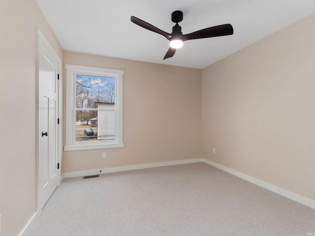 spare room with a ceiling fan, visible vents, baseboards, and light carpet