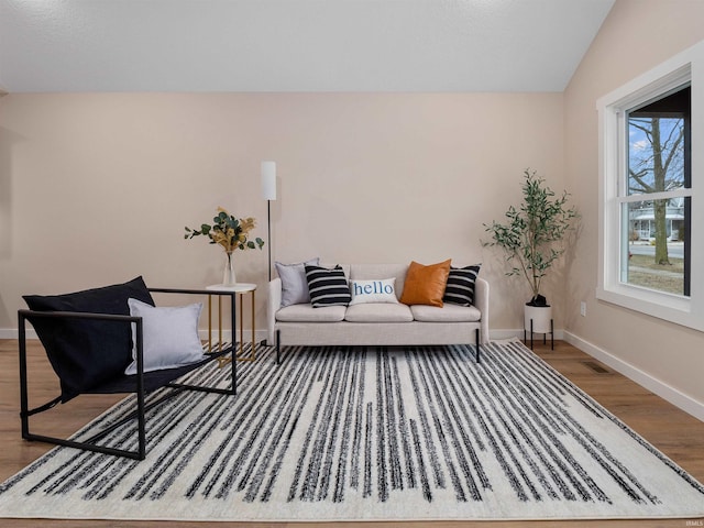 living area featuring visible vents, wood finished floors, baseboards, and lofted ceiling