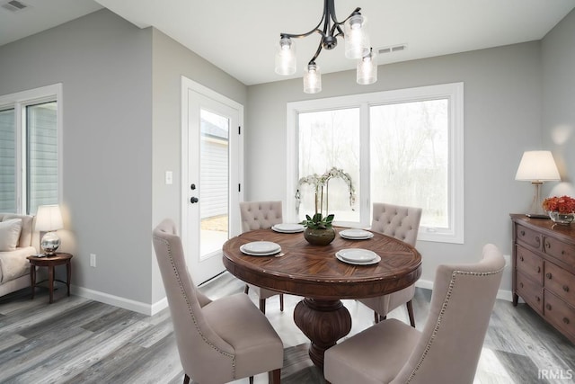 dining space featuring a notable chandelier, visible vents, baseboards, and light wood-style floors