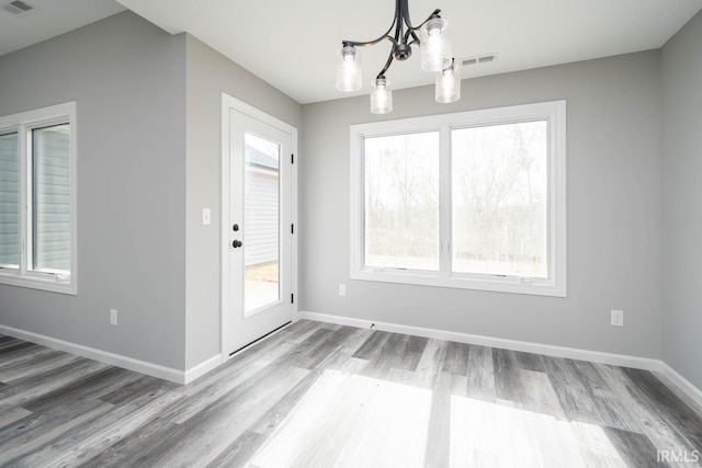 unfurnished dining area with a wealth of natural light, baseboards, and wood finished floors