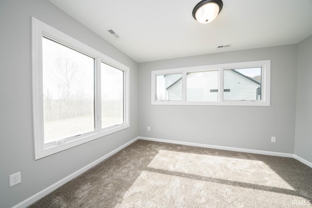 carpeted spare room featuring visible vents, baseboards, and a healthy amount of sunlight