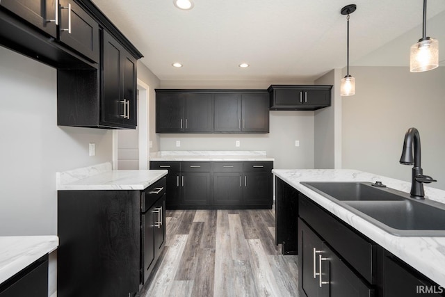 kitchen featuring a sink, pendant lighting, light wood-type flooring, recessed lighting, and dark cabinets