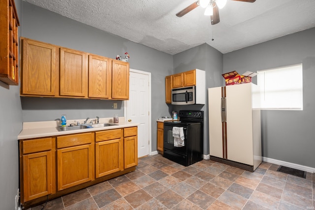 kitchen with stainless steel microwave, light countertops, freestanding refrigerator, black electric range oven, and a sink