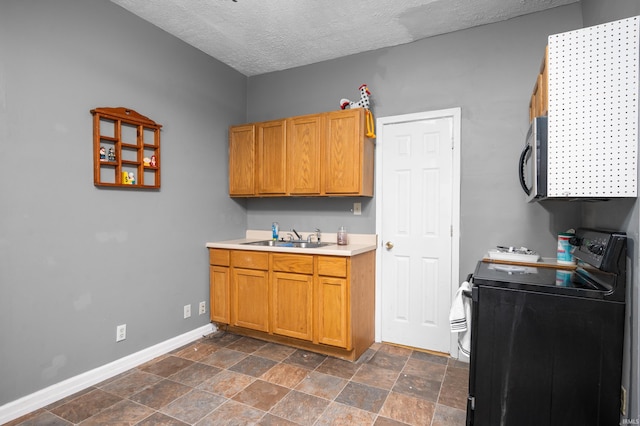 kitchen with stainless steel microwave, baseboards, light countertops, black electric range, and a sink