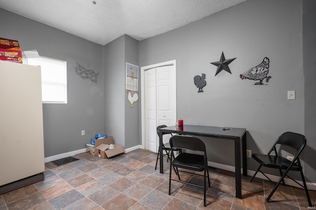 home office with stone finish flooring, baseboards, and a textured ceiling