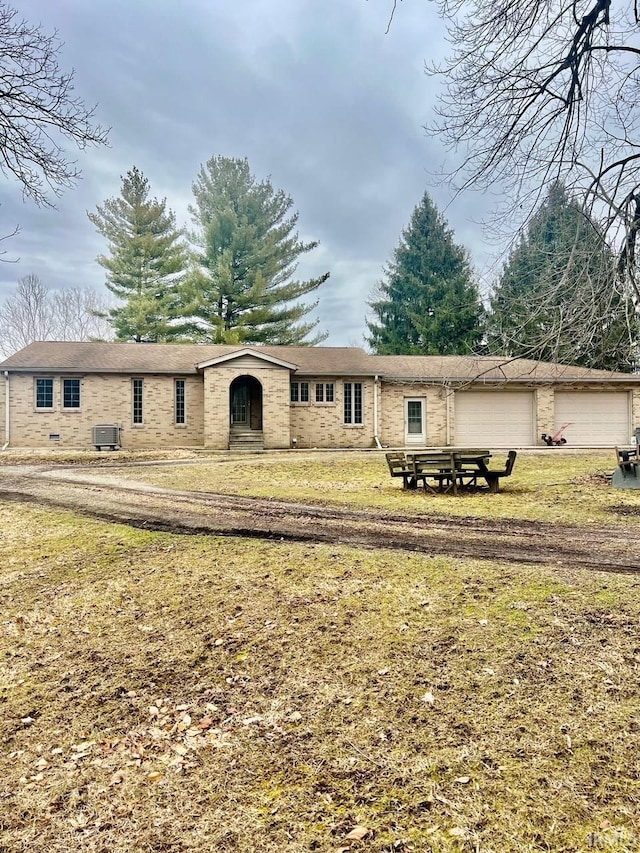 ranch-style home with a garage, brick siding, cooling unit, and a front lawn