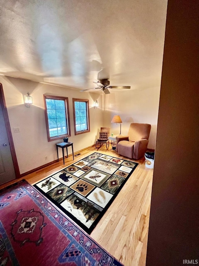 living area with ceiling fan, baseboards, and wood finished floors