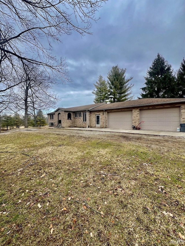 ranch-style home featuring brick siding, a garage, driveway, and a front lawn