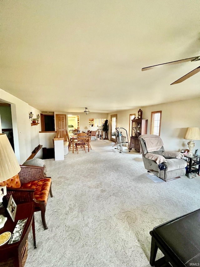 living area with a ceiling fan and carpet