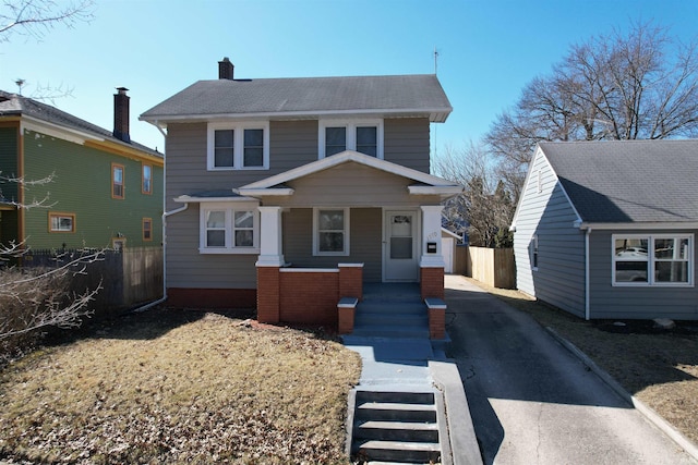 american foursquare style home featuring a chimney, driveway, and fence