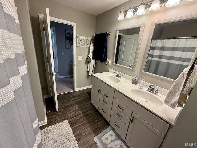 full bathroom with double vanity, wood finished floors, baseboards, and a sink