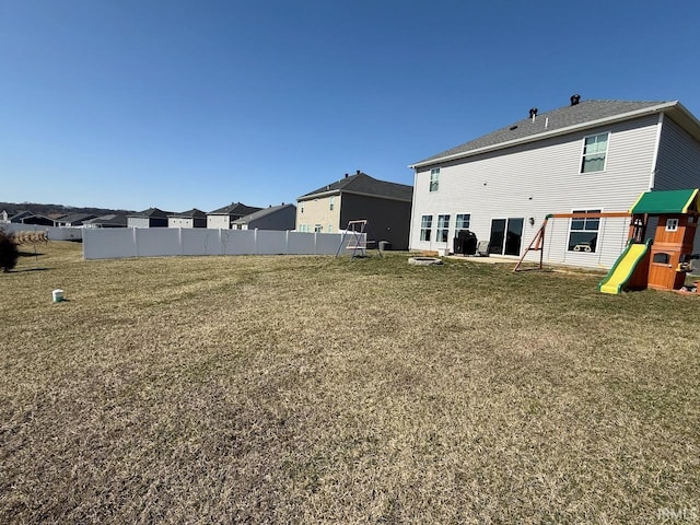 back of house with a playground, fence, a lawn, and a residential view