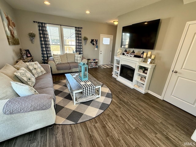 living area featuring dark wood finished floors, a glass covered fireplace, recessed lighting, and baseboards