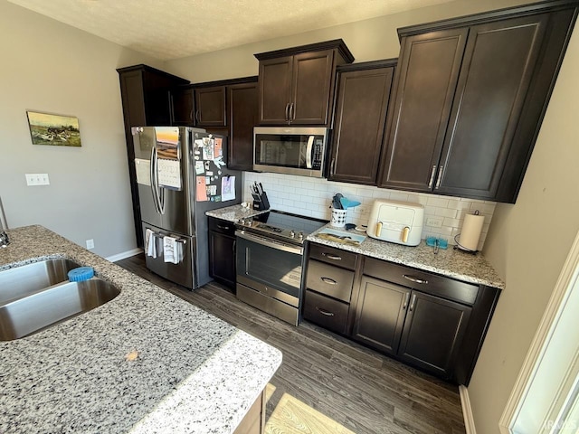 kitchen with dark brown cabinetry, backsplash, appliances with stainless steel finishes, and dark wood finished floors