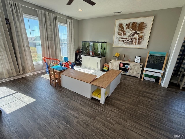 interior space featuring baseboards, visible vents, dark wood-style flooring, and ceiling fan