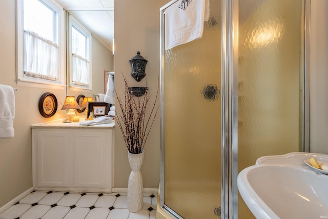 bathroom featuring a sink, baseboards, a shower stall, and tile patterned floors