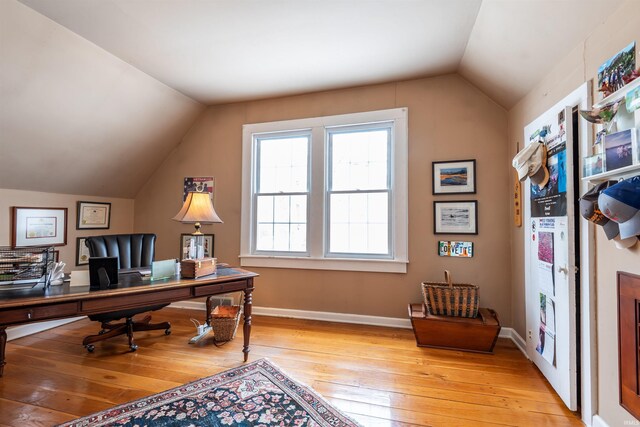 home office with baseboards, light wood-style floors, and vaulted ceiling