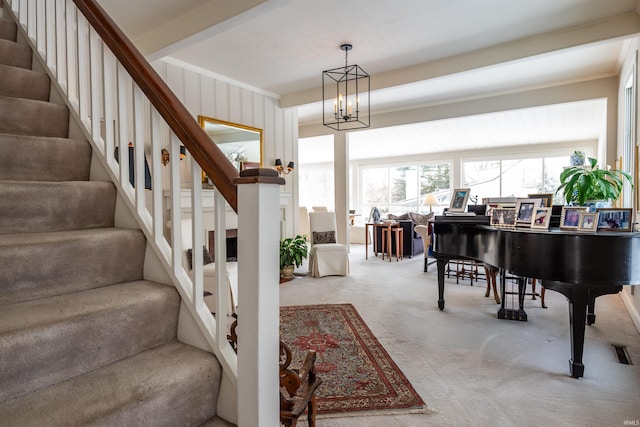 carpeted entrance foyer featuring a notable chandelier, stairway, crown molding, and beam ceiling