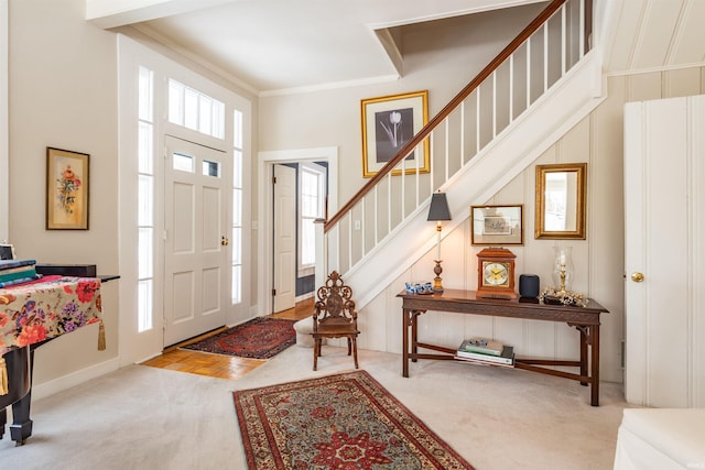 carpeted foyer entrance with crown molding, stairway, and baseboards