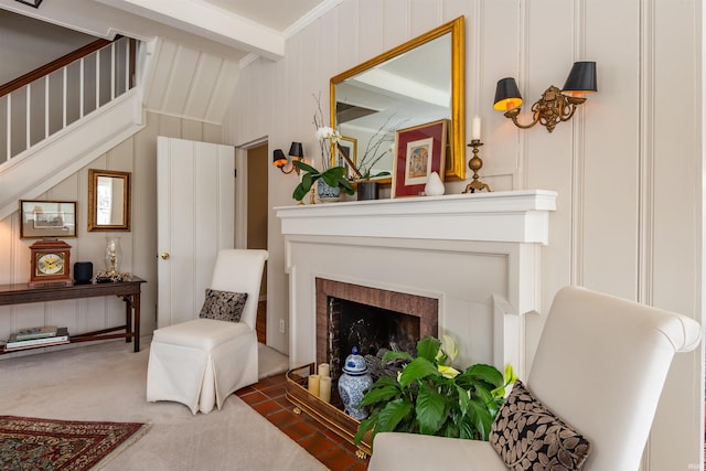 sitting room featuring beamed ceiling, a fireplace with flush hearth, carpet floors, crown molding, and stairs