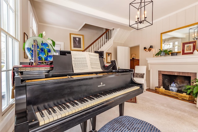 interior space featuring a brick fireplace, crown molding, stairway, carpet flooring, and a notable chandelier