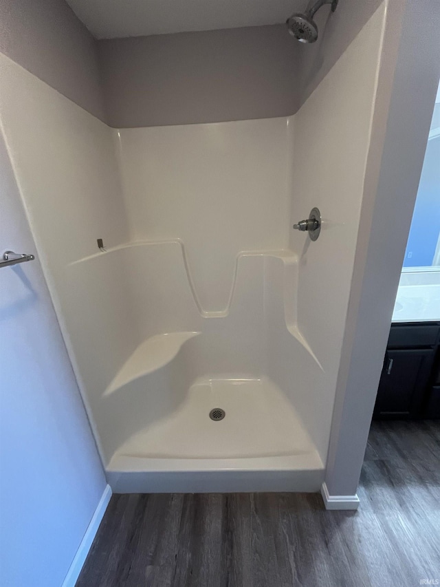 bathroom with wood finished floors, baseboards, and a shower