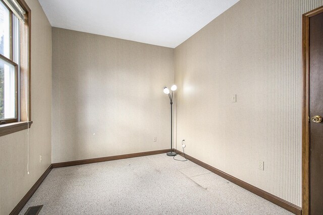 carpeted empty room with visible vents, wallpapered walls, and baseboards