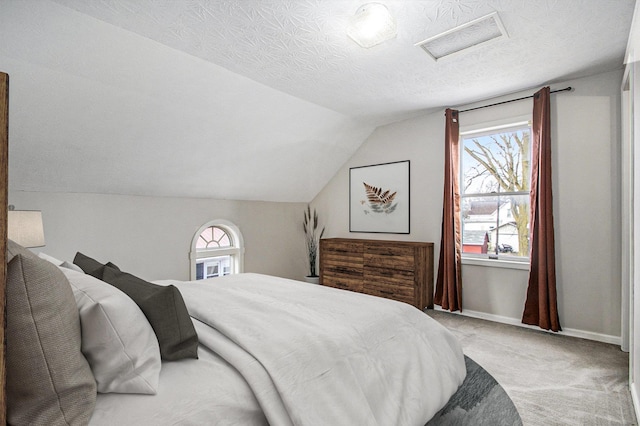 bedroom with light carpet, multiple windows, a textured ceiling, and vaulted ceiling