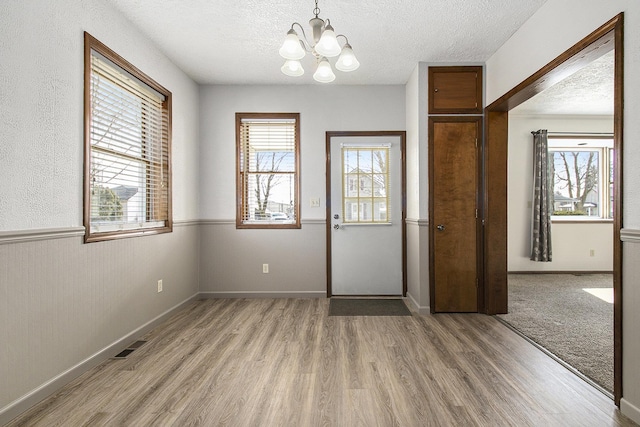 foyer with a healthy amount of sunlight, a textured ceiling, and light wood-style flooring