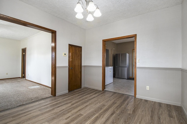 empty room featuring wood finished floors, a wainscoted wall, and a textured ceiling