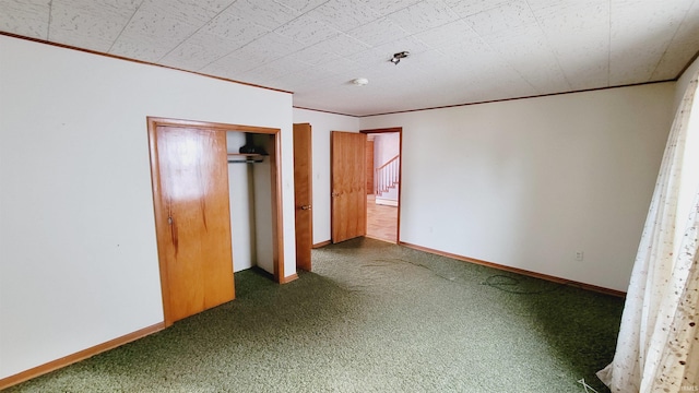 unfurnished bedroom with a closet, carpet flooring, baseboards, and ornamental molding