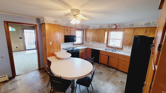 kitchen with a sink, black appliances, stone finish floor, light countertops, and brown cabinets