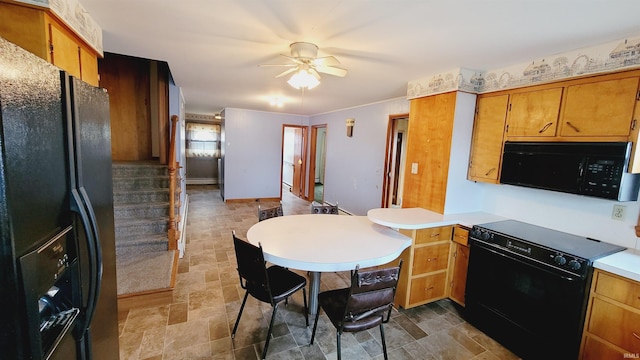 kitchen with brown cabinets, black appliances, stone finish flooring, a peninsula, and light countertops