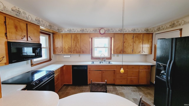 kitchen featuring a sink, black appliances, light countertops, and a healthy amount of sunlight