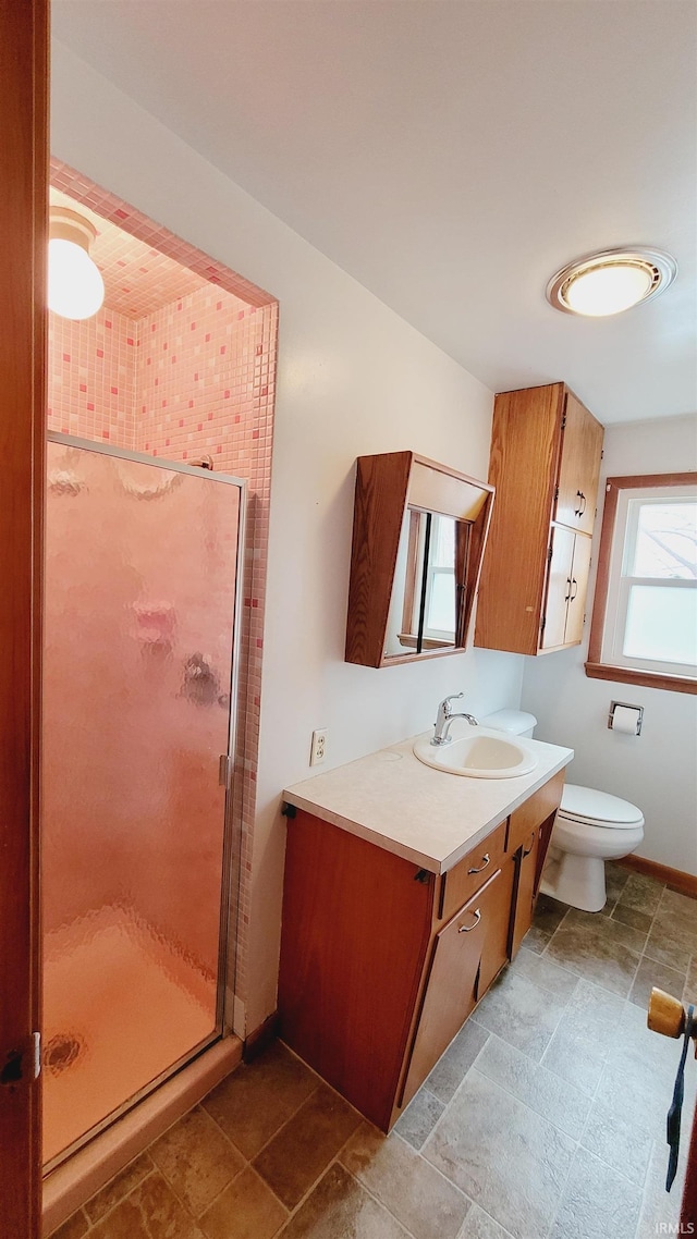 full bath featuring vanity, toilet, baseboards, and a stall shower