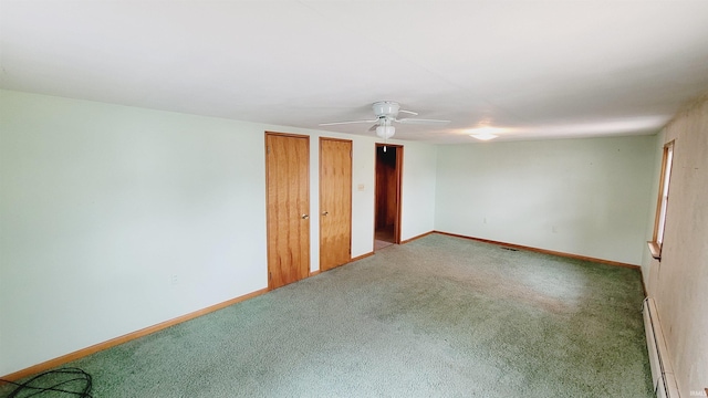 unfurnished bedroom featuring a baseboard heating unit, carpet, baseboards, and two closets