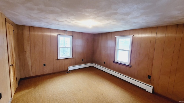 carpeted empty room featuring a wealth of natural light, baseboards, baseboard heating, and a textured ceiling