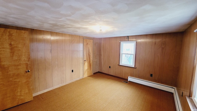 unfurnished room with baseboards, baseboard heating, and wood walls