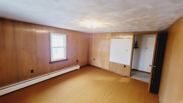 carpeted empty room with wooden walls, baseboards, and a baseboard radiator