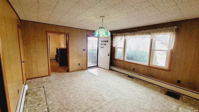 unfurnished dining area featuring wood walls, carpet floors, and a baseboard radiator