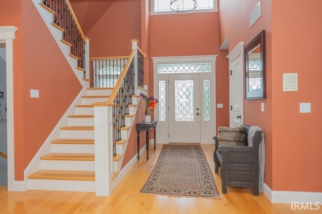 entrance foyer featuring a towering ceiling, wood finished floors, and a wealth of natural light