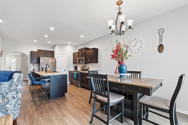 dining area with recessed lighting, arched walkways, an inviting chandelier, light wood finished floors, and baseboards