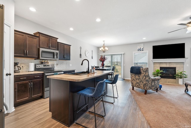 kitchen featuring a sink, decorative backsplash, dark brown cabinetry, appliances with stainless steel finishes, and open floor plan