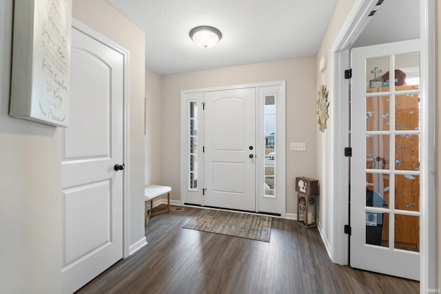 foyer entrance with baseboards, a textured ceiling, and dark wood-style flooring